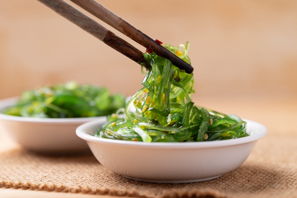 wakame seaweed salad with sesame seed in a bowl with chopsticks