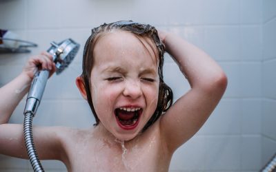 close up of young child singing in shower while washing hair